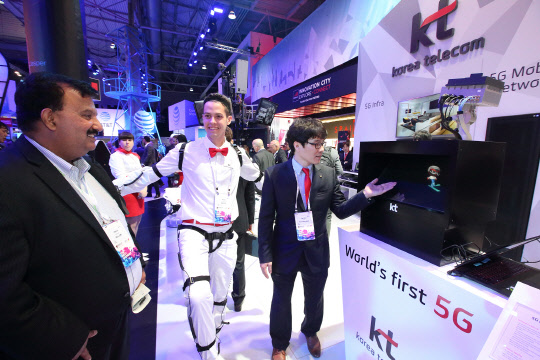 KT는 27일(현지시간)부터 스페인 바르셀로나에서 열린 모바일월드콩그레스(MWC) 2017에서 평창 5세대(G) 이동통신 규격 기반 '5G 네트워크 환경(5G End-to-End 네트워크)'를 공개했다고 밝혔다. 회사 부스 전시요원이 모션센서가 부착된 웨어러블 기기를 착용하고 움직이면 '5G 네트워크 환경'을 통해 홀로그램이 스튜디오에 전송되는 것을 관람객에게 설명하고 있다. <KT 제공>